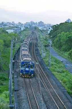 Tayvan Demiryolları İdaresi R20 dizel-elektrikli lokomotif şehir merkezinde elektrik kabloları olan yük arabalarını çekiyor..