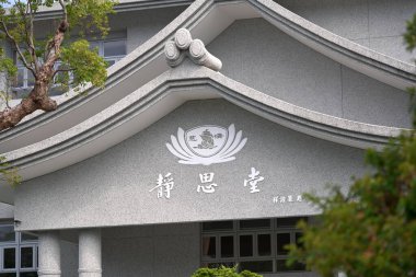 Tayvan - 20 Eylül 2025: Gri desenli duvarları olan Tzu Chi Jing Si Salonu, beyaz süslemeli çok katlı çatı, dairesel nilüfer amblemi ve tabela, ağaçların çerçeve kenarları, Budist mimarisi, Tayvan.