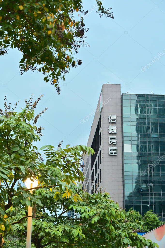 Taiwan - Oct. 26, 2025: Sinyi Realty headquarters with vertical Chinese signage, modern glass and stone facade, corporate logo atop, cloudy sky behind, leading Taiwan property agency.