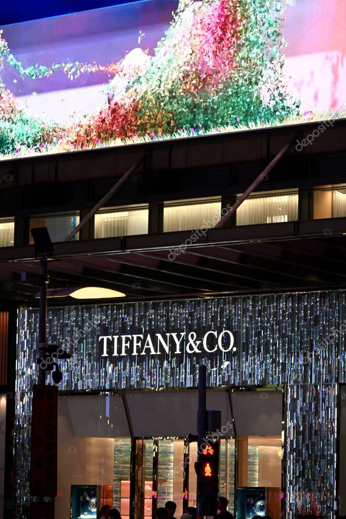 Taiwan - Oct. 26, 2025: Tiffany & Co. storefront with sparkling mosaic wall and large colorful digital screen above, illuminated windows and pedestrians below at night.