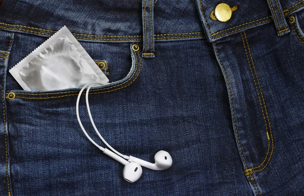 Preservativos em pacote e fones de ouvido em jeans — Fotografia de Stock