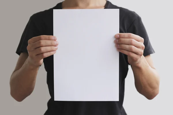 Людина тримає білий папір A4 вертикально — стокове фото