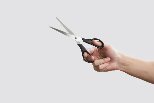 Scissors in hand. Isolated on grey background — Stock Photo, Image