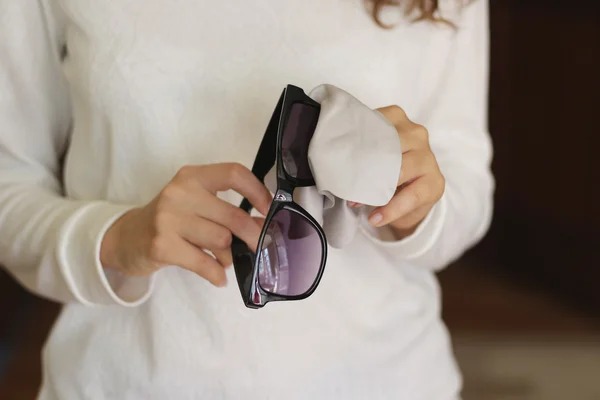 Women hand cleaning black sunglasses lens with blur brown backgr — 图库照片