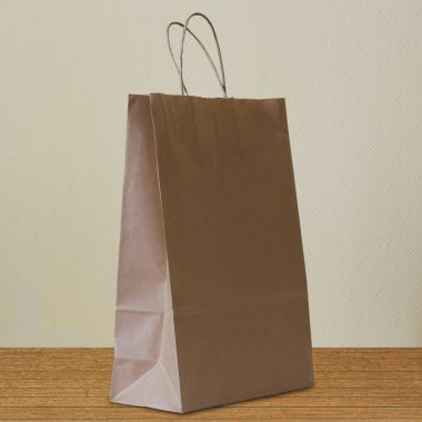 Kahverengi kağıt torba kulplu bir ahşap zemin üzerinde duruyor.