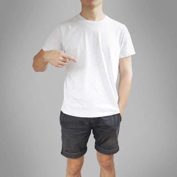 Giovanotto con camicia bianca, davanti. Indicando una t-shirt . — Foto Stock