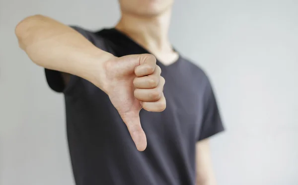 Jovem de t-shirt preta mostrando um sinal de antipatia, isolado o — Fotografia de Stock