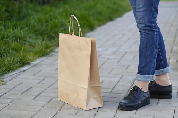 Chica en zapatos hermosos está junto a una bolsa de papel . —  Fotos de Stock