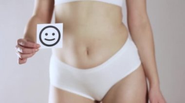 Kızın yüzünde gülen bir ifade var. Gri bir arkaplanda.