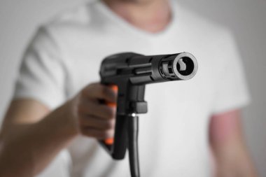 Adamın elinde yüksek basınçlı çamaşır makinesi var. Yakın plan. Gri bir arkaplanda izole edilmiş.