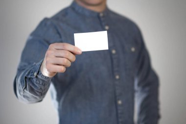 Adamın birinin elinde beyaz bir kartvizit var. Bir adamın elinde bir kağıt. Mesajın için hazır. Gri bir arkaplanda izole edilmiş.