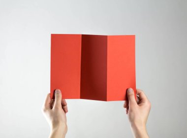 Ellerinde üç katlı kırmızı el ilanı var. Elinde temiz bir el ilanı. Mesajın için. Gri bir arkaplanda izole edilmiş.