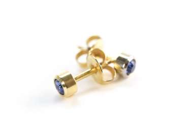 Altın küpeler. Kapatın. Beyaz bir arkaplanda izole edilmiş.