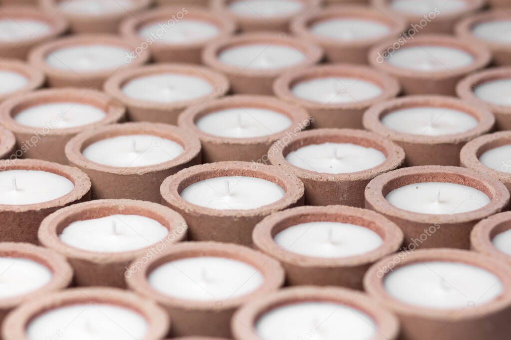 Production of scented candles. Lots of white candles in a concrete candle holder. Close up.