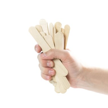 The hand holds wooden spatulas. Close up. Isolated on a white background.
