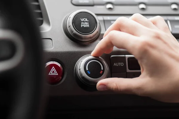 The hand adjusts the air conditioner in the car. Close up.