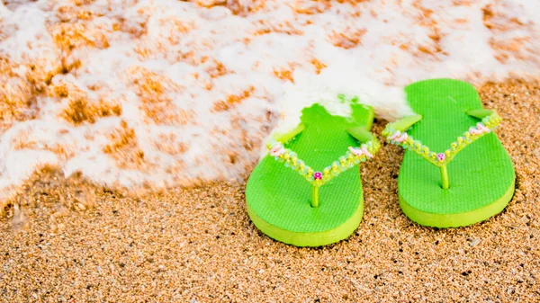 Sandálias verdes das mulheres na praia . — Fotografia de Stock