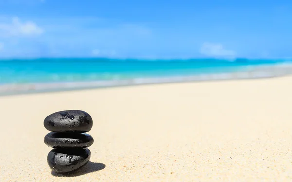 Pedras pretas equilibradas em uma praia tropical . — Fotografia de Stock