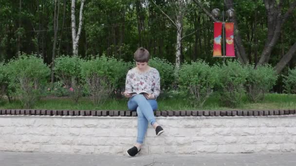 Дівчина читає книгу в парку Стокове Відео 