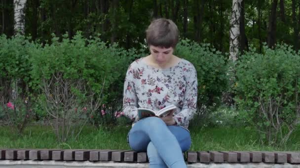 Meisje leest een boek in het park — Stockvideo