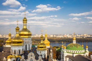 Ortodoks Kilisesi 'nin güzel sarı ve altın kubbeleri mavi gökyüzünün ve şehrin arka planına karşı. Kiev-Pechersk Lavra Katedrali 'nin Kubbeleri.