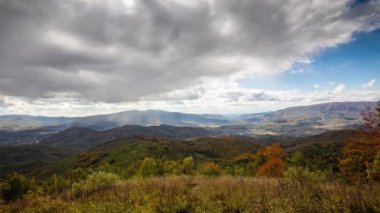 Sonbahar dağlarında güzel bir zaman atlaması. Dağlarda güneş ışınları. Sarı dağ zirveleri, sonbahar ağaçları. Bulutlar, bulutlar mavi gökyüzüne doğru hareket ediyor..