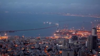 Dağdan Haifa şehrinin güzel akşam manzarası. Büyük bir İsrail limanı. Sokak lambaları sokakları ve şehri aydınlatıyor..