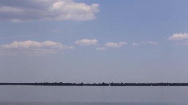 Nehrin yatların yelken açtığı güzel bir manzarası. Gökyüzünde beyaz bulutlar var..