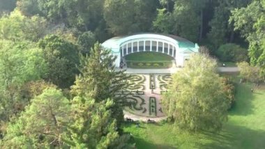 Yazın parkın üzerinde güzel bir uçuş. Yeşil yapraklı ağaçlar. İnsanlar yeşil bir çayırda yürüyorlar. Güneşli hava.