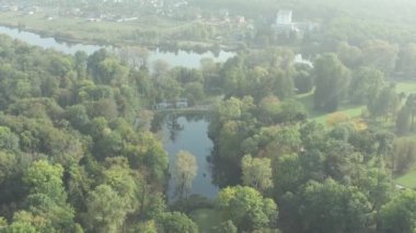 Yazın parkın üzerinde güzel bir uçuş. Yeşil yapraklı ağaçlar. İnsanlar patika boyunca yürür. Güneşli hava.