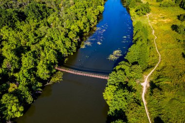 Nehrin üzerindeki asma köprünün üst görüntüsü. Yeşil orman, çimen ve patika.