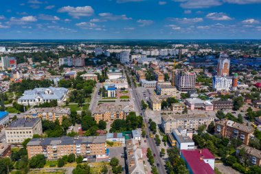 Şehrin güzel yaz manzarası. Çatı evleri, yollar, arabalar, yeşil yapraklı ağaçlar..