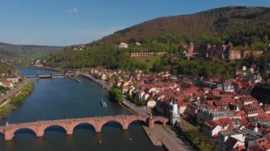 Nehrin üzerindeki yaya köprüsü. Heidelberg kalesinin ve şehrin eski kısmının güzel manzarası. Bahar. Ağaçlarda yeşil yapraklar. Nekka Nehri. Güzel dağlar.