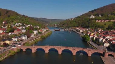 Nehrin üzerindeki yaya köprüsü. Heidelberg kalesinin ve şehrin eski kısmının güzel manzarası. Bahar. Ağaçlarda yeşil yapraklar. Nekka Nehri. Güzel dağlar.