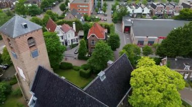 Evler, ağaçlar ve dar sokaklar ile çevrili merkezi taştan bir kilise ve uzun çan kulesiyle tarihi cazibeyi barışçıl bir kırsal alan ile harmanlayan tuhaf bir kasabanın havadan görünüşü..