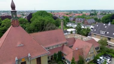 Kırmızı çatılı saat kulesi, yeşil kulesi ve yemyeşil çevresi olan Avrupa kentinin havadan görünüşü. Konut cazibesi ve işaretli yolların ortasındaki tarihi süs eşyası..