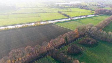 Kırsal alanların havadan görünüşü çitlere, kanallara ve dağınık ağaçlara bölünmüş su yamaçları, patikalar ve canlı kırsal alanlardaki uzak çiftlik evleri ile güneşlendirilmiş manzaralar..