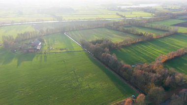 Kırsal alanların ekin sıraları, ağaç gölgeleri, kanal ve tarım, altyapı ve doğal geometriyi harmanlayan güneşli manzarası.