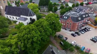 Beyaz kilise ve modern tuğladan daireleri olan küçük bir kasabanın havadan görünüşü yeşillik çerçevelerini mimari kontrastı.