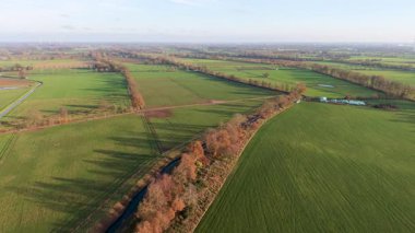 Kırsal alanların ekin sıraları, ağaç gölgeleri, kanal ve tarım, altyapı ve doğal geometriyi harmanlayan güneşli manzarası.