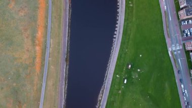 Barajın havadan görünüşü, kontrol yapısı, sızıntı havzası ve kavisli inşaat mühendisliği ile karışık doğal-endüstriyel bir arazide yol geçen su kanalı gibidir..