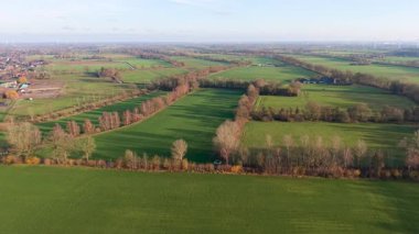 Kırsal alanların ekin sıraları, ağaç gölgeleri, kanal ve tarım, altyapı ve doğal geometriyi harmanlayan güneşli manzarası.