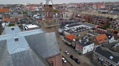 Hollanda 'nın tarihi tuğla kulesinin havadan görünüşü. Saat ve tahta çatılı kulesi. Güneş panelli modern evler..