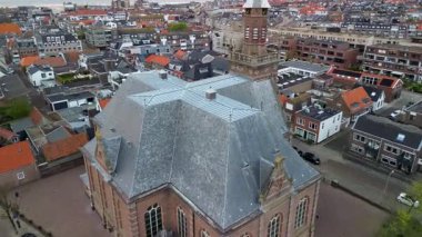 Tahta çatı ve çan kulesiyle Avrupa 'nın tarihi kilisesinin havadan görünüşü kırmızı kiremitli ve modern binaların yoğun karışımı..