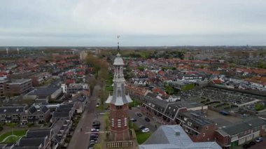 Hollanda 'nın hava manzaralı kilise kulesi. Kırmızı kiremitli evler, mezarlıklar ve dar sokaklar üzerinde yükselen horoz rüzgar gülü. Yoğun, ahenkli şehir manzarası..