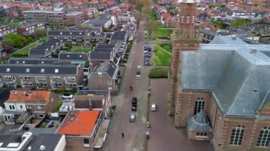 Hollanda 'nın gotik kilisesinin hava manzarası saat kulesi, kemerli pencereler ve yoğun kentsel şebekedeki karanlık çatılı evler..