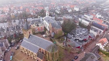 Çan kulesi, beyaz şapel, kanal ve kırmızı çatılı evlerle Hollanda 'nın gotik kilisesinin havadan görünüşü, tarihi cazibeyle dolu yoğun ve düzenli bir şehir düzeni oluşturuyor..