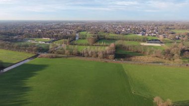Kırsal alanların ekin sıraları, ağaç gölgeleri, kanal ve tarım, altyapı ve doğal geometriyi harmanlayan güneşli manzarası.
