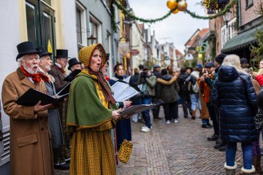 Deventer, Overijssel, Hollanda - 14.12.2025: Charles Dickens Festivali 'nde. Viktorya dönemi Noel şarkıcıları sokak çelenklerinde, kostümlerde ve kış kalabalığında şarkı söylüyorlar..