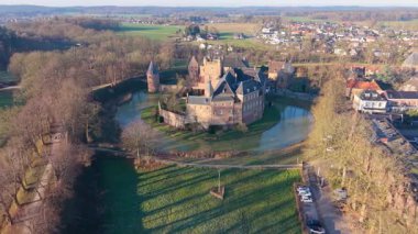 Geniş hendeği olan bir ortaçağ şatosu yüksek bir kilisenin yanında duruyor. Kümelenmiş evler, açık araziler, ağaçlık yollar ve ormanlarla çevrili. Uyumlu tarihi bir manzara oluşturuyor..